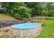 Above ground pool with a wooden deck and pergola in a fenced backyard with mature trees at 1301 Ficklen Church Way, Canton, GA 30114