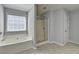 Bright bathroom featuring large tub, glass door shower, window with blinds, and gray tile floors at 3805 Roxwood Park Dr, Buford, GA 30518