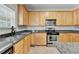 Kitchen featuring wood cabinets, stainless steel appliances, and granite countertops at 3805 Roxwood Park Dr, Buford, GA 30518