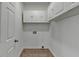 Small, clean laundry room with white cabinets and tile floors at 3805 Roxwood Park Dr, Buford, GA 30518