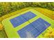 Overhead view of two pristine blue tennis courts surrounded by green foliage at 3805 Roxwood Park Dr, Buford, GA 30518