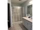 Bathroom featuring a glass-enclosed shower, light tile flooring, and a single-sink vanity at 802 Village Pl, Loganville, GA 30052