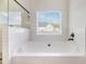Bright bathroom featuring a soaking tub with tile surround and backyard views at 461 Barnwood Dr, Rockmart, GA 30153