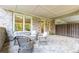 Inviting covered patio featuring classic brickwork, tiled floors and comfortable wicker furniture at 502 Abbington River Ln, Atlanta, GA 30339