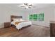 Comfortable main bedroom featuring wood flooring, a rustic wood bed frame, and a view of the fenced yard at 3455 Henderson Dr, Cumming, GA 30041