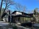 Two-story home exterior with glass-enclosed sunroom, black siding, brick chimney, and a well-manicured yard at 4601 Tall Pines Nw Dr, Atlanta, GA 30327