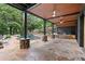 A covered patio featuring stone floors, ceiling fans, and a stone pool surround creating a luxurious outdoor living space at 4601 Tall Pines Nw Dr, Atlanta, GA 30327