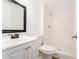 White bathroom with tile shower, wood-look floors, toilet and vanity with black trimmed mirror at 2174 Rexford Dr, Decatur, GA 30034