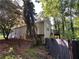 Back of home with a deck overlooking a wooded yard and a damaged fence at 3230 Plymouth Rock Dr, Douglasville, GA 30135