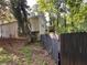 Back of home with a deck overlooking a wooded yard and a damaged fence at 3230 Plymouth Rock Dr, Douglasville, GA 30135