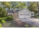 Home with an attached two-car garage, and driveway, surrounded by mature trees and landscaping at 2701 Log Cabin Se Dr, Atlanta, GA 30339