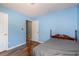 A light-blue bedroom featuring dark-wood floor, baseboards, and a doorway to another room at 1478 Elena Dr, Mcdonough, GA 30253