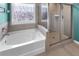 Bright bathroom featuring a soaking tub, a glass-enclosed shower, and tiled walls with a window at 216 Orchard Trl, Canton, GA 30115