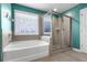 Bathroom features a soaking tub, glass-enclosed shower, tile walls, and a window for natural light at 216 Orchard Trl, Canton, GA 30115