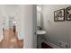 Stylish powder room featuring a pedestal sink, decorative mirror, and elegant wall art, adjacent to a hallway at 3600 Goldenrod Dr, Alpharetta, GA 30005