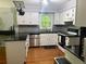 Bright kitchen with white cabinets, stainless steel appliances, black countertops, and wood floors, ideal for cooking at 507 Spring Creek Ne Way, Marietta, GA 30068