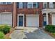 Brick townhome exterior featuring attached garage, a blue door and fresh landscaping at 3187 Mill Springs Cir, Buford, GA 30519