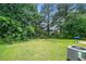 Backyard featuring a well-manicured lawn, mature trees, and partial view of a home at 6279 Marbut Farms Rd, Lithonia, GA 30058