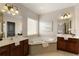 Bright bathroom featuring dual vanities, a large soaking tub, and decorative lighting fixtures at 239 S Village Sq, Canton, GA 30115