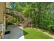 A view of the back of the house showing a concrete patio and wood steps leading up to a higher level deck at 6960 Worley Rd, Cumming, GA 30028