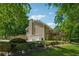 Exterior elevation showing a two-car garage, brick chimney, and a deck, all surrounded by a beautifully landscaped lawn at 6960 Worley Rd, Cumming, GA 30028