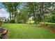 Expansive backyard featuring a lush green lawn, mature trees, pond, and manicured landscaping at 12162 Mountain Laurel Dr, Roswell, GA 30075