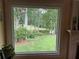 Window view of the lush backyard with mature trees, manicured lawn, and serene pond at 12162 Mountain Laurel Dr, Roswell, GA 30075
