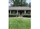Inviting covered front porch with white pillars, trimmed hedges and ferns, enhancing the home's curb appeal at 12162 Mountain Laurel Dr, Roswell, GA 30075