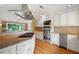 Island kitchen features stainless appliances, gas cooktop, double oven, light cabinets, and view to living area at 12162 Mountain Laurel Dr, Roswell, GA 30075