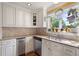 Classic kitchen with light cabinets, stainless dishwasher, double sinks, and window overlooking backyard at 12162 Mountain Laurel Dr, Roswell, GA 30075