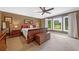 Spacious primary bedroom with a large window, elegant furniture, and warm tones at 12162 Mountain Laurel Dr, Roswell, GA 30075
