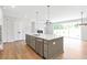 Open-concept kitchen with a large island, modern appliances, hardwood floors, and access to the living area at 206 Grady Burrell Dr, Holly Springs, GA 30115