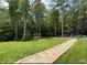 Expansive backyard featuring a stone pathway leading to an outdoor lounge area amidst a backdrop of tall trees at 605 Red Leaf Way, Canton, GA 30114