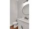 Half bath features a modern round mirror, white vanity, and white toilet at 118 Via Roma, Woodstock, GA 30188