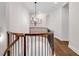 Hallway features a chandelier, wood floors, and wood and black railing at 118 Via Roma, Woodstock, GA 30188
