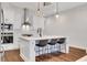 A modern kitchen features an island with barstool seating, pendant lights, and stainless appliances at 118 Via Roma, Woodstock, GA 30188