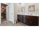 Bathroom featuring double sinks, white countertops, brown cabinets and a view into the walk-in closet at 211 Serendipity Way, Dallas, GA 30157