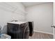 A well-organized laundry room with black appliances, white shelving, and wood-look flooring at 211 Serendipity Way, Dallas, GA 30157
