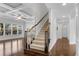 Staircase with wooden banister and carpeted stairs adjacent to open living room at 431 La Perla Dr, Sugar Hill, GA 30518