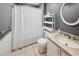 Neutral bathroom with tiled floors, shower and tub with curtain, white shelving unit, and a round mirror at 51 Vienna Way, Douglasville, GA 30134