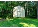 Shed with white crossbeam doors nestled among mature trees in a grassy backyard at 51 Vienna Way, Douglasville, GA 30134