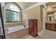 Bathroom features a soaking tub, travertine tile, and custom wood accents at 511 Etris Ct, Roswell, GA 30075