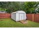 View of a metal shed on a wooden foundation pad, located in the backyard with a wood fence and trees at 618 Nw Summerville Dr, Lawrenceville, GA 30046