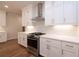 Modern kitchen featuring stainless oven and range hood, white cabinets, and hardwood flooring at 512 Winston Croft Cir # 56, Johns Creek, GA 30022