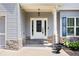 Close-up of front porch with stone accents, a white door with sidelights, and manicured landscaping at 1016 Buckeye Ln, Villa Rica, GA 30180