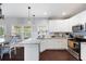 Sunlit kitchen boasts an island, white cabinets, stainless appliances and hardwood flooring at 1016 Buckeye Ln, Villa Rica, GA 30180