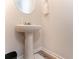 Compact pedestal sink bathroom featuring hardwood floors and a round mirror at 11730 Chatham Dr, Hampton, GA 30228