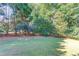 Lush, green backyard featuring mature trees and grass at 5115 Amberden Hall Dr, Suwanee, GA 30024