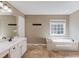 Bright bathroom with a large window above the soaking tub and a double sink vanity at 5115 Amberden Hall Dr, Suwanee, GA 30024