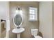 Powder room features a pedestal sink, oval mirror, and natural light from window at 5115 Amberden Hall Dr, Suwanee, GA 30024